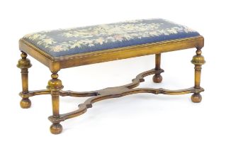 A William and Mary style long stool with a needlework drop in seat raised on turned tapering legs