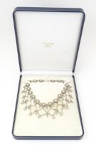A white metal festoon choker necklace with silver cabochon and bead detail. 15" long Please Note -