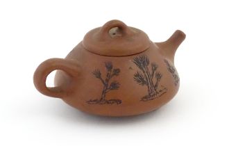 A Chinese Yixing teapot with incised tree and script detail. Character marks under and to