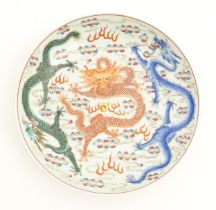 A Chinese famille rose plate decorated with three dragons and a flaming pearl amongst stylised