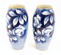 A pair of large French porcelain vases, the blue ground decorated with roses and foliage, signed