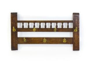 An early 20thC oak coat rack / hat rack with a finial turned back panel and seven brass hooks. 27"