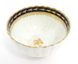 An English tea bowl with lobed detail, banded gilt borders and gilt foliate motif to centre.