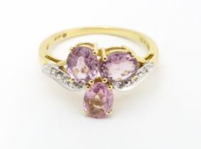 A 10k gold ring set with diamonds and a trio of pink stones. Ring size approx. L Please Note - we do