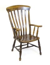 A late 19thC / early 20thC lathe back Windsor armchair, with swept arms, a shaped seat and raised on