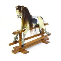 A 20thC carved and painted rocking horse with painted features, leather style saddle, metal stirrups