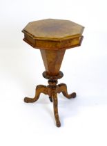 A Victorian walnut sewing table, with a moulded octagonal top, trumped shaped pedestal with carved