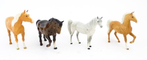 Four Beswick models of horses comprising a palomino Prancing Arab model no. 1261, a brown horse with