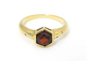 A 9ct gold ring set with central hexagonal garnet flanked by two diamonds to each shoulder Ring size