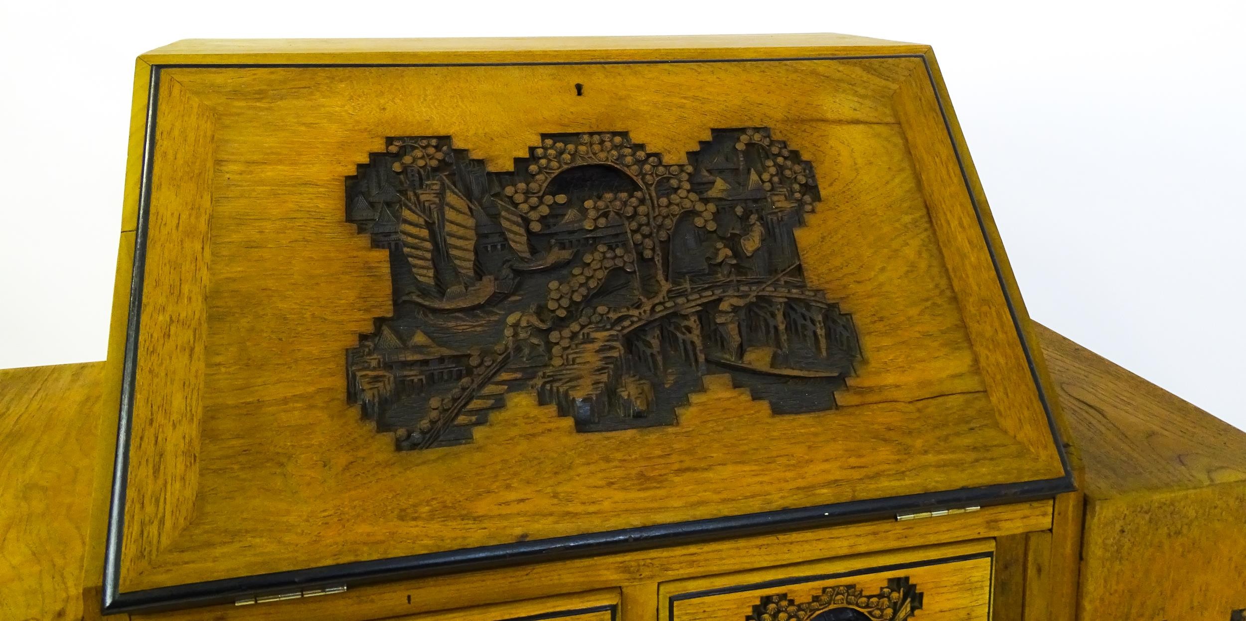 An early / mid 20thC Teak bureau accompanied by a stool, with carved oriental scenes to the front, - Image 6 of 12