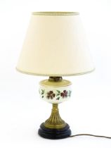 A table lamp formed from an oil lamp with cream glass reservoir with hand painted flower detail.