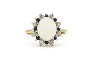 A 9ct gold ring set with central opal cabochon bordered by blue and white stones. Ring size