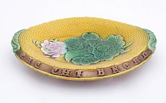 A Victorian majolica bread plate with flowers and foliage to centre, the rim with motto Eat the