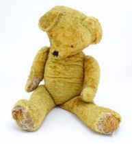 Toy: A large 20thC straw filled teddy bear with a stitched nose and mouth, and articulated limbs.
