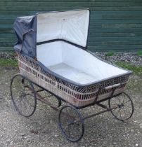 A large Victorian pram / spinal / invalid carriage. The wicker bassinette body on a four wheel