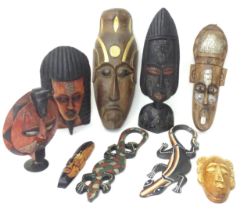 A quantity of assorted carved wooden masks with incised and applied detail. Together with carved