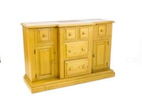 A modern pine sideboard with a moulded breakfront top, five short drawers and two panelled cupboards