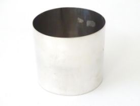 A white metal beaker of circular form. Approx. 3 1/4" high Please Note - we do not make reference to