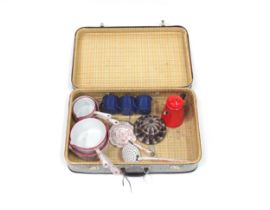 A mid 20thC suitcase containing an assortment of enamelled kitchen ware, comprising: a set of four
