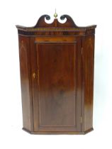 A 19thC mahogany corner cupboard with carved pediment and brass finial, decorated with herringbone