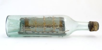 A 20thC scratch built ship in bottle with postcard backdrop depicting a waterfront with boats and