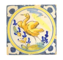 A Continental Delft style tile depicting a bird within a roundel, with shaped detail to corners.