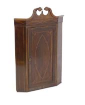 A Georgian mahogany corner cupboard with a swans neck pediment decorated with starburst detailing,