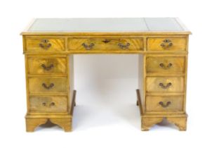 A late 20thC double pedestal desk with two banks of four short graduated drawers flanking a single