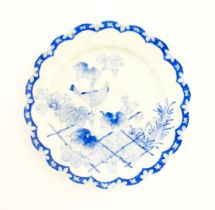 A Japanese blue and white plate with scalloped edge, decorated with a bird perched on a branch