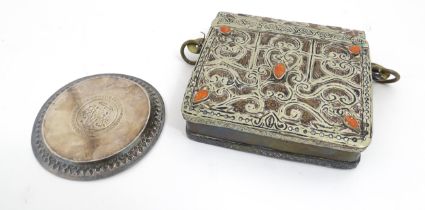 An Islamic brass Quran case with hinged lid, scrolling decoration and applied cabochon style detail.