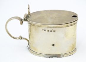 A silver mustard pot of oval form with blue glass liner, hallmarked Birmingham 1914, maker George