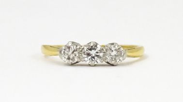 An 18ct gold ring with a trio of platinum set diamonds. Ring size approx. N Please Note - we do
