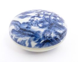 A Chinese blue and white ink box of circular form decorated with figures in a landscape scene with a