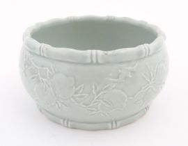 A Chinese celadon planter decorated in relief with peaches and bat detail, and stylised bamboo rims.