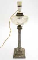 A table lamp formed from an oil lamp with silver plate Corinthian column and cut glass reservoir.