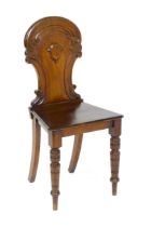 A Victorian mahogany hall chair with a carved backrest and raised on turned tapering front legs