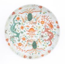A Chinese plate / dish decorated with dragons, phoenix birds, flaming pearls and floral detail.
