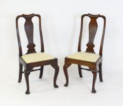 A pair of early 18thC walnut side chairs with a vase shaped back splat, drop in seat and raised on