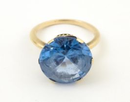 A gold ring set with central facet cut blue stone. Ring size approx. N 1/2 Please Note - we do not