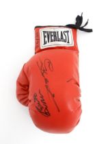 A red Everlast boxing glove with autographs signed by Roberto Duran and Sugar Ray Leonard. Approx.