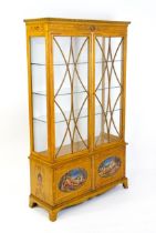 An Edwardian satinwood cabinet with a dentil moulded cornice above two astragal glazed doors, the