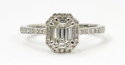 A platinum ring set with central diamond bordered by further diamonds and flanked by further