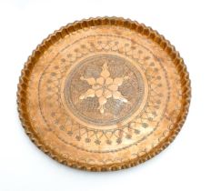 A 20thC copper tray with pie crust edge decorated with central flower motif and punchwork banded