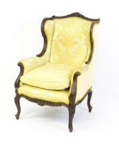 A late 19thC / early 20thC walnut wingback armchair with a chamfered and moulded frame, the chair