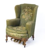 A 19thC wingback armchair for re-upholstery, the chair raised on walnut cabriole front legs and
