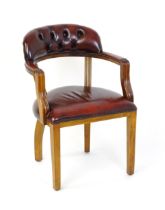 A late 20thC leather upholstered desk chair with a bowed back and deep buttoned upholstery , the