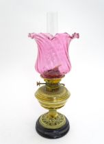 A brass oil lamp with no. 2 Hinks Lever burner and flared cranberry glass shade. Approx. 21" high
