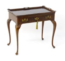 An Edwardian burr walnut topped silver table with a raised edge having pierced handles, the frieze