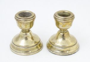 A pair of squat silver candlesticks hallmarked Birmingham 1978, maker W. I. Broadway & Co. Approx. 2