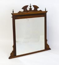 An Aesthetic movement mahogany over mantle mirror with a carved pediment and turned finials above